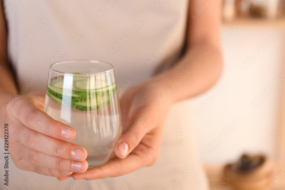 Woman holding glass with tasty fresh cucumber water, closeup