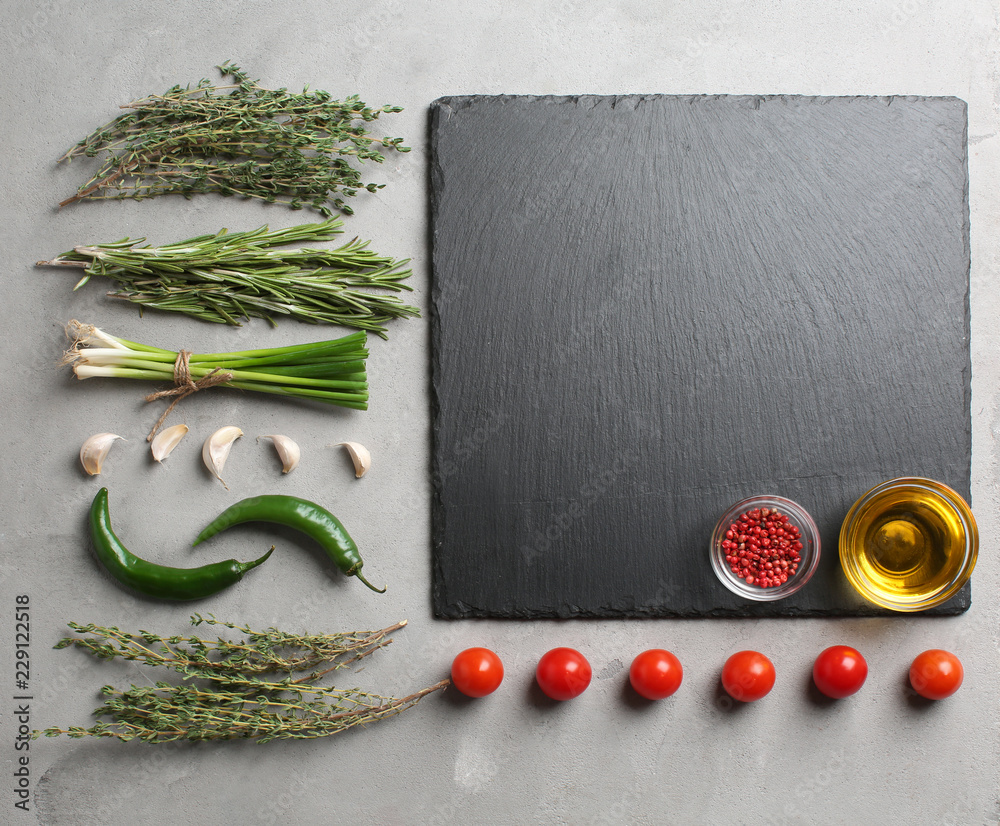Flat lay composition with fresh herbs and slate plate on grey background