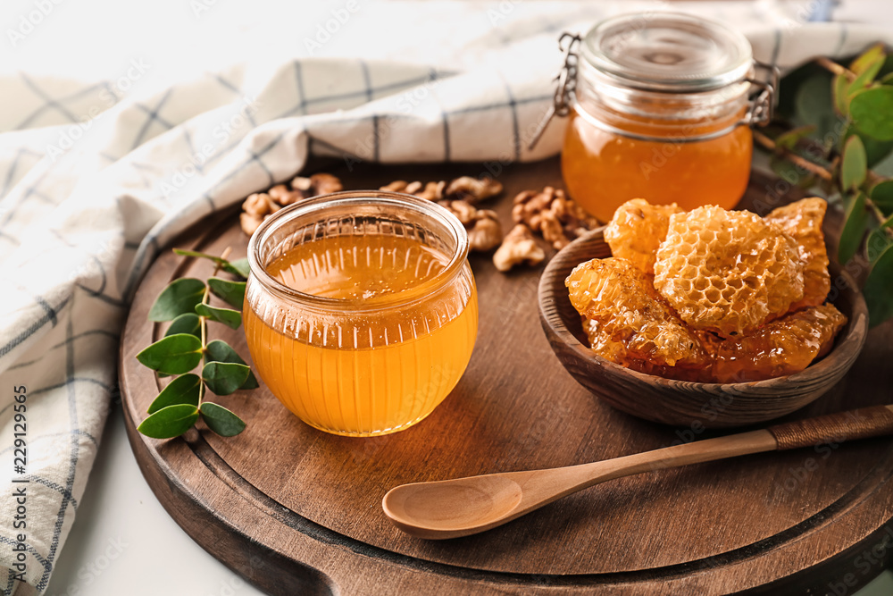 装有蜂窝的碗和木板上装满蜂蜜的罐子