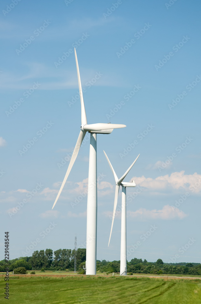 绿色田野和蓝天背景下的风力涡轮机
