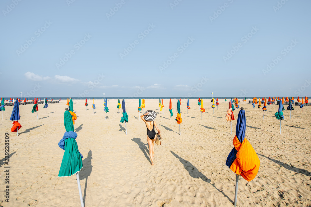 诺曼底著名的法国度假胜地多维尔，一名妇女打着五颜六色的雨伞走在海滩上