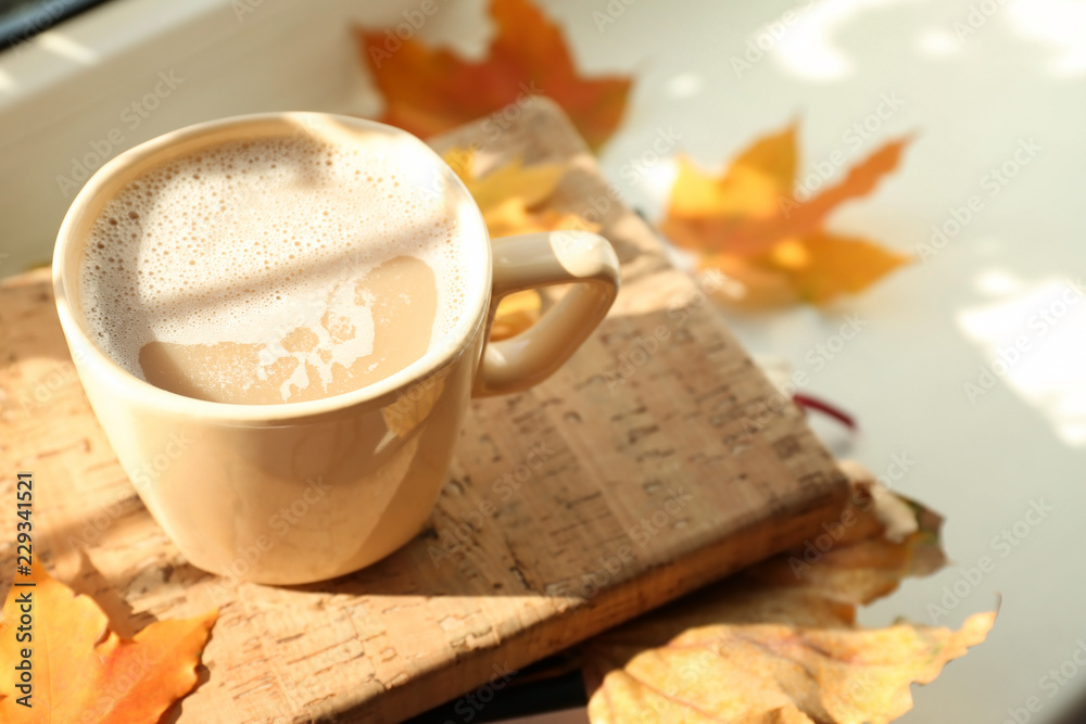 一杯热咖啡，窗台上有书和秋叶，特写