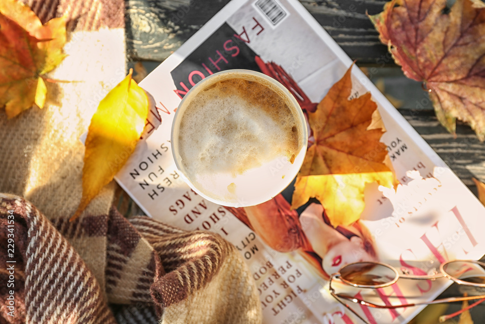 一杯热咖啡，木凳上放着杂志和秋叶