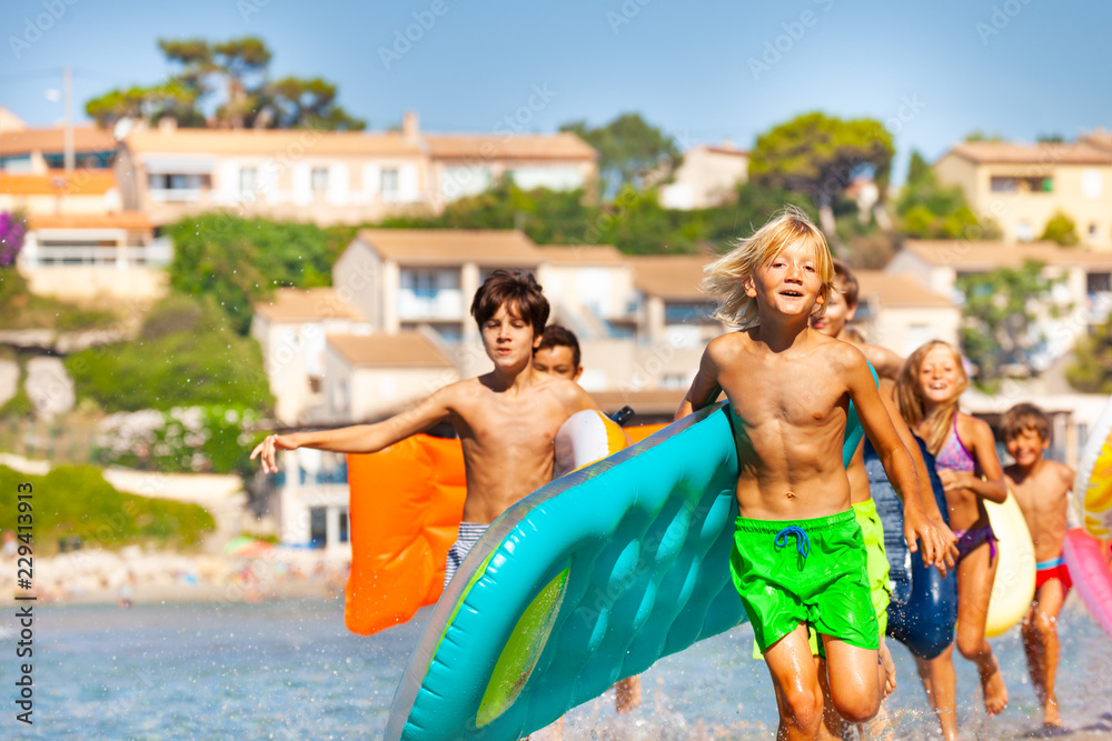 快乐的男孩和他的朋友们沿着海滩奔跑