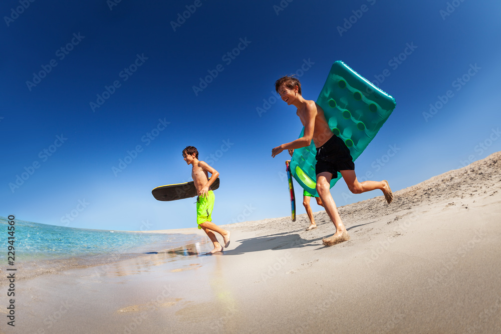 年轻冲浪者在海滩上用冲浪板跑步