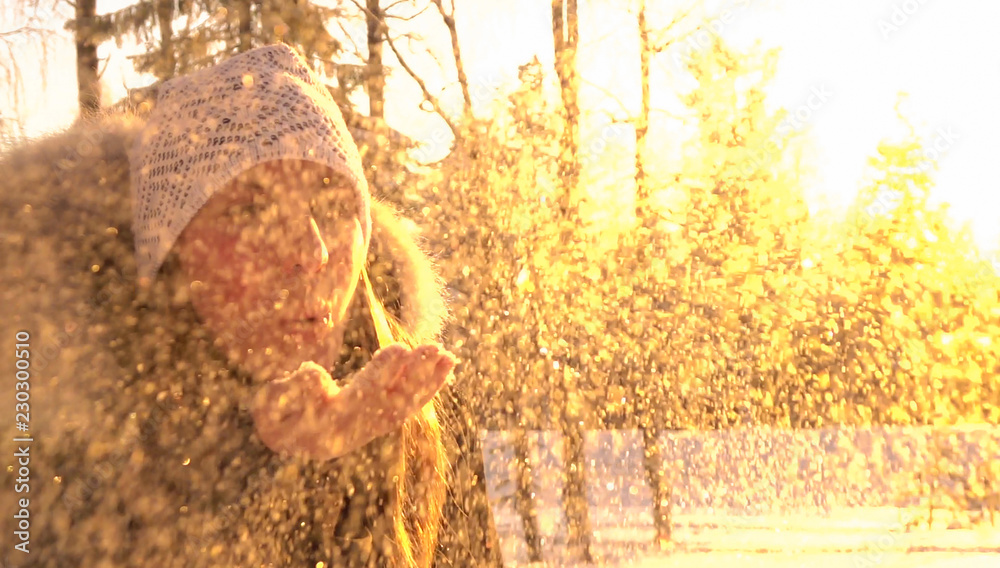 特写：日出时，兴高采烈的女游客从手中吹出新鲜的雪。