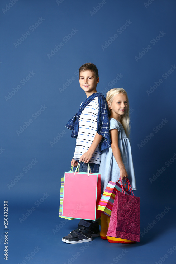 可爱的男孩和女孩拿着购物袋，背景是时尚的衣服