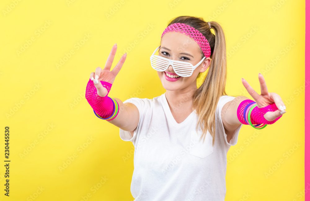 Woman in 1980s fashion giving the peace sign on a split yellow background