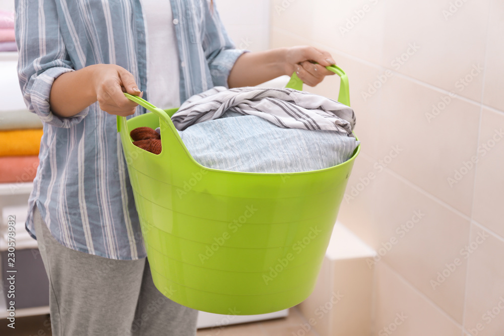 浴室里拿着装有脏衣服的洗衣篮的女人