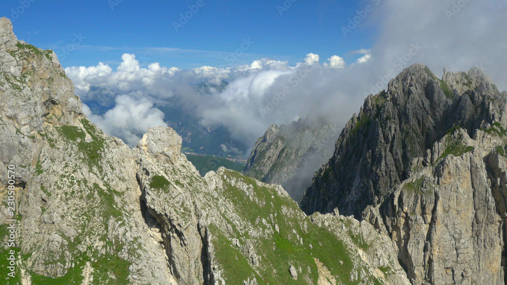 航空：阳光明媚的斯洛文尼亚，白色的薄雾和云朵在岩石山脉上翻滚。