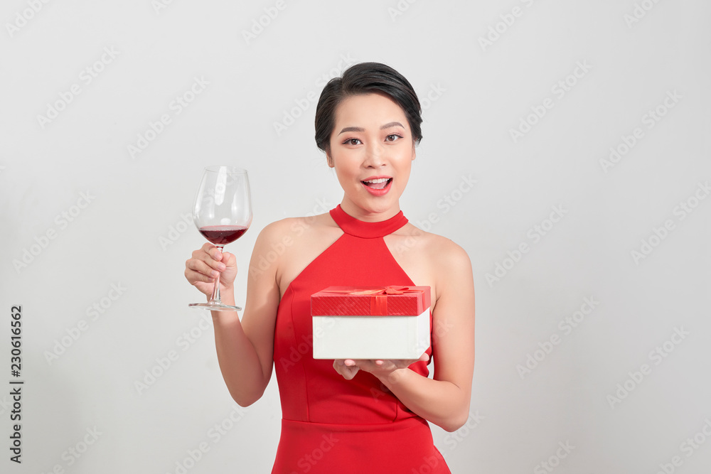 年轻微笑的女人拿着圣诞礼盒。一个拿着酒杯的美丽女孩的独立画像o