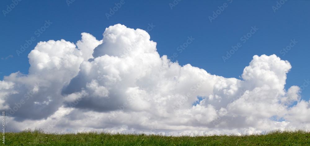 美丽的翻滚的云朵在深蓝色的天空和韦尔丘顶部的草地上升起