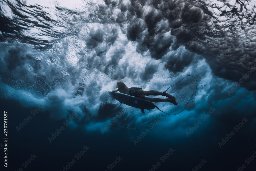 Professional surfer with surfboard dive underwater. Alone surfer and big ocean wave.