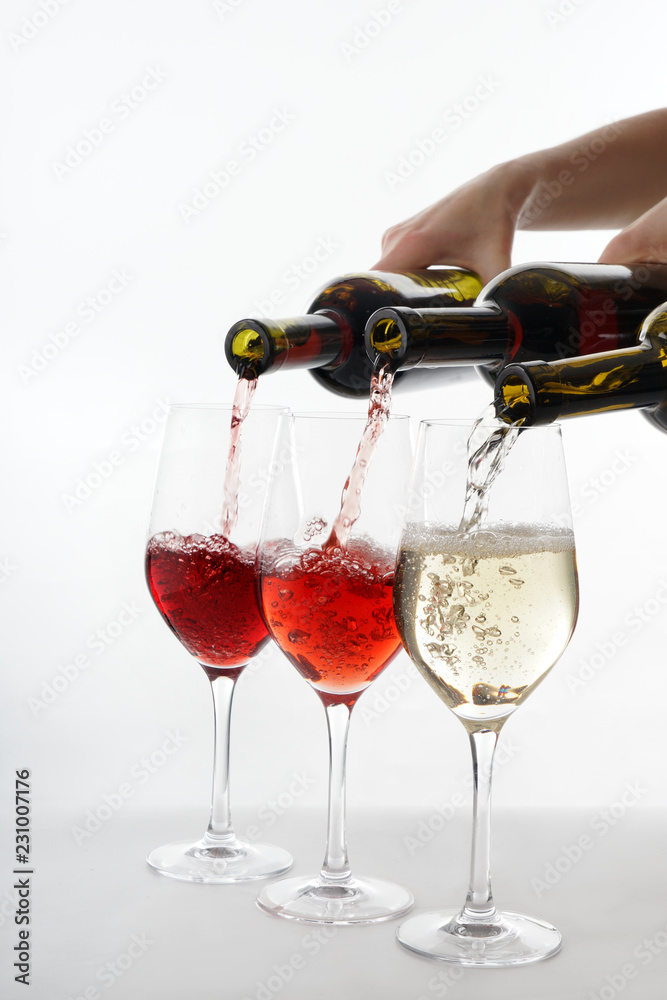 将不同的葡萄酒从瓶子倒入白底玻璃杯