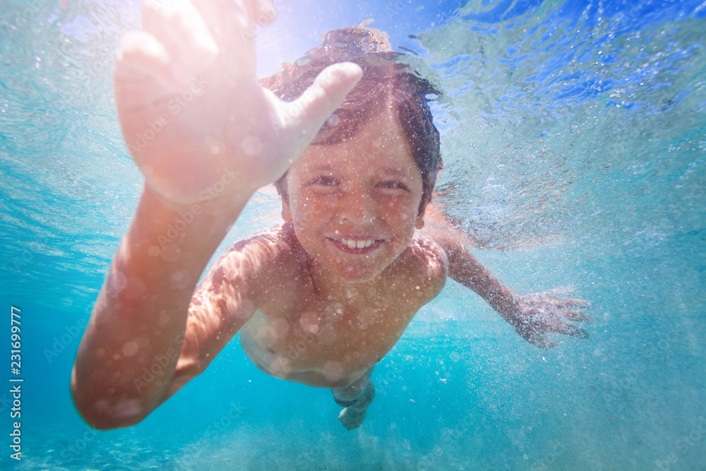 Happy boy enjoying swimming underwater in summer