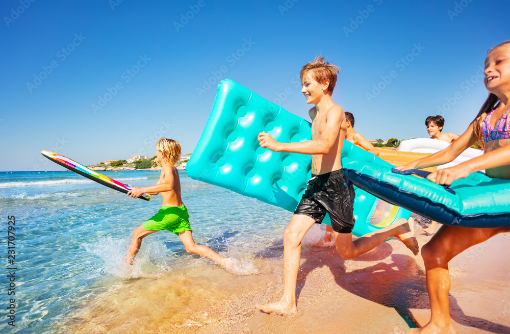 Happy teenagers running into the sea in summer