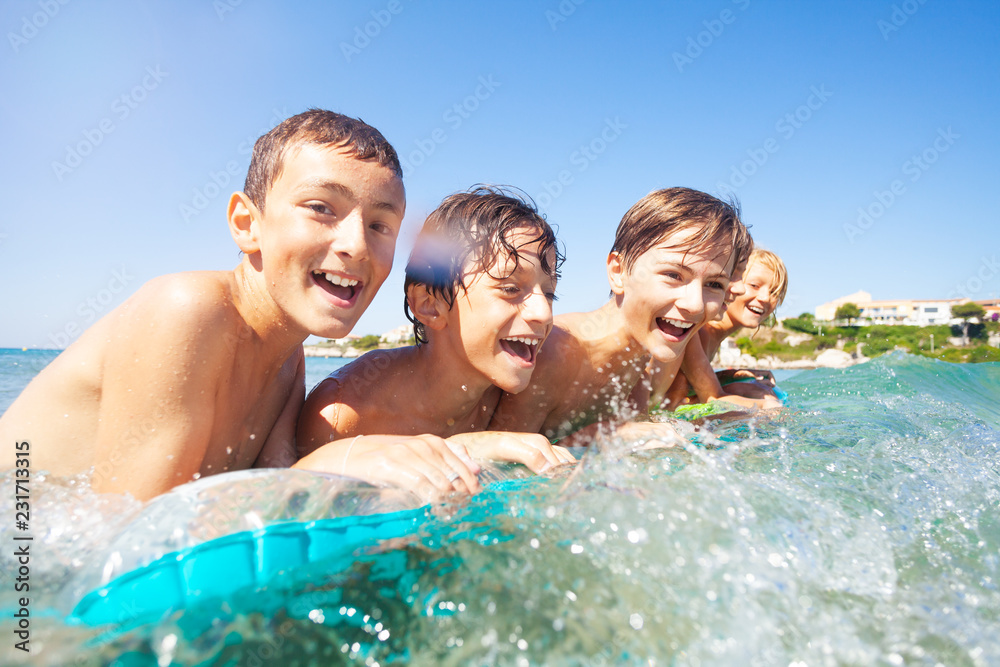 快乐的男孩们在气垫上在海里游泳