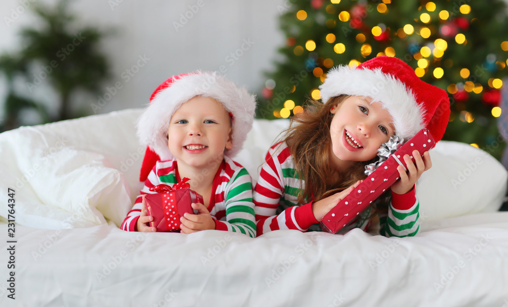 圣诞节早上，圣诞树附近，穿着睡衣带着礼物的快乐孩子