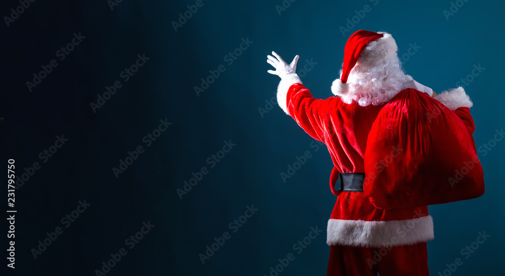 圣诞老人拿着一个深蓝色背景的红色袋子