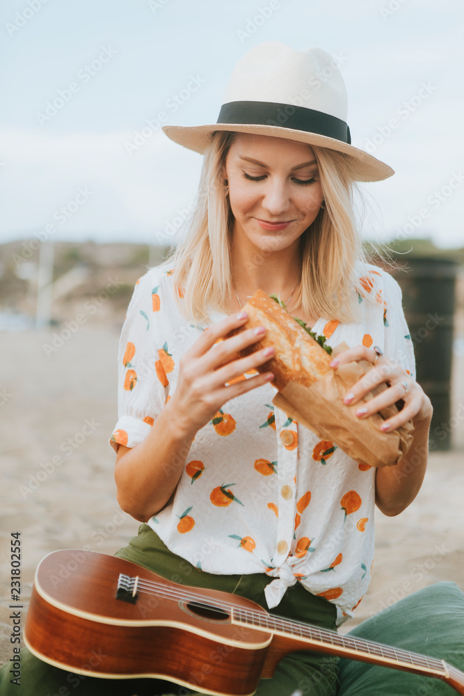 海滩野餐时吃三明治的女人