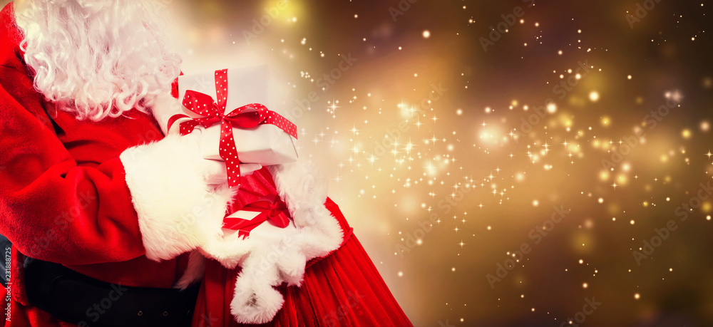 圣诞老人拿着一个红色袋子里的礼物盒，背景是闪亮的灯光