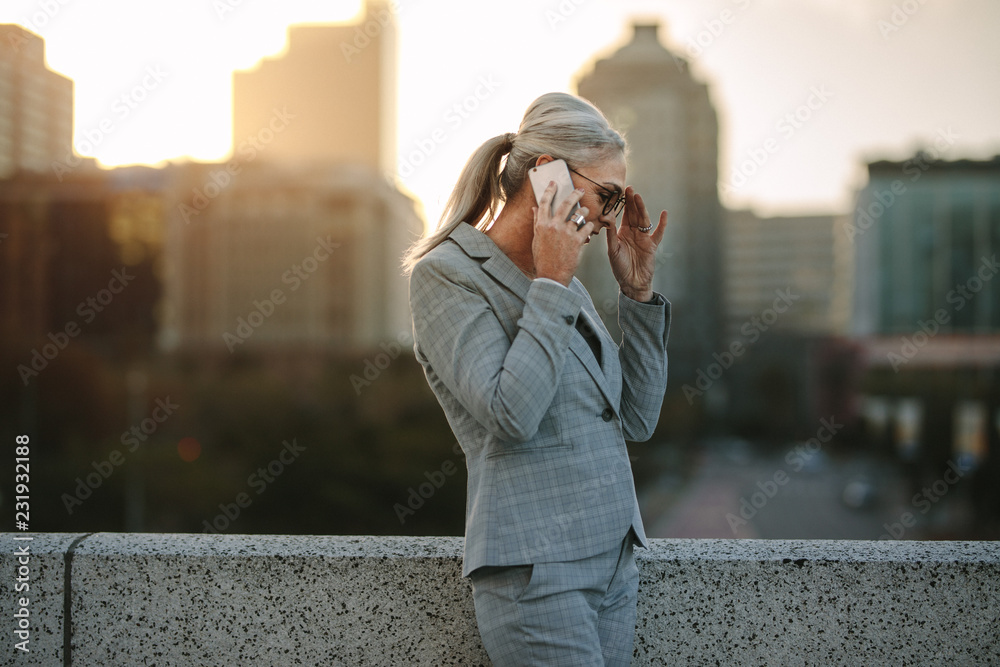 Senior businesswoman talking on phone on city bridge