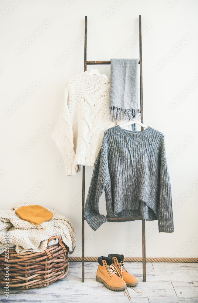 挂在衣架上的秋冬保暖针织衫，白墙背景。时尚女性冬装。W