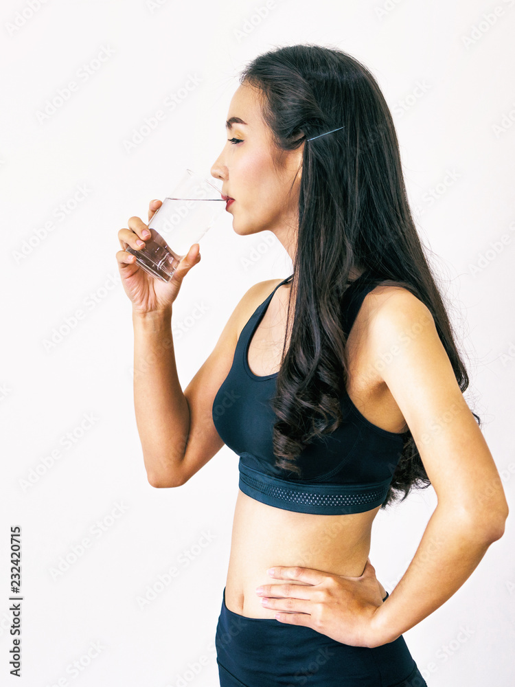 穿着运动服的女人在健身馆喝水。健康的生活方式和补水理念。
