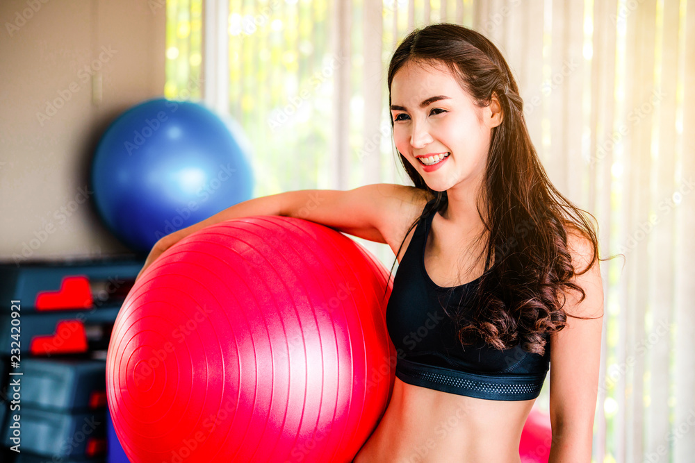Beautiful young woman in fitness center doing pilates exercise with fitness ball. Healthy lifestyle 