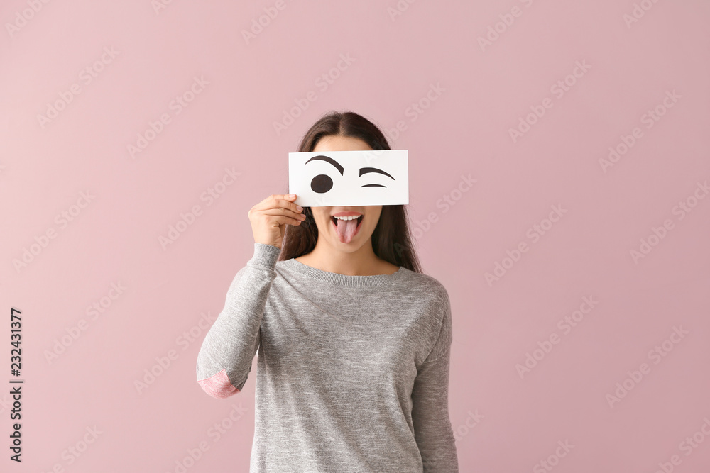 情绪激动的年轻女子把脸藏在纸后面，彩色背景上画着眼睛