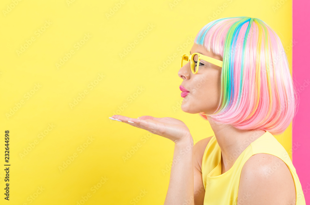 戴着彩色假发的女人在黄色和粉色的背景上接吻