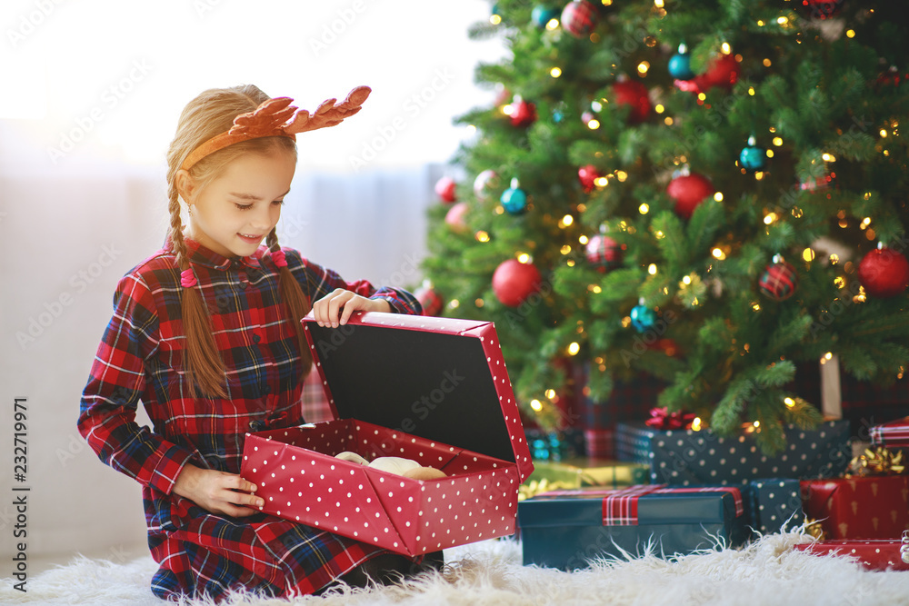 快乐的小女孩，早上在树旁拿着圣诞礼物