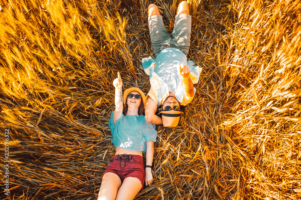 相爱的情侣躺在麦田上，指着天空微笑