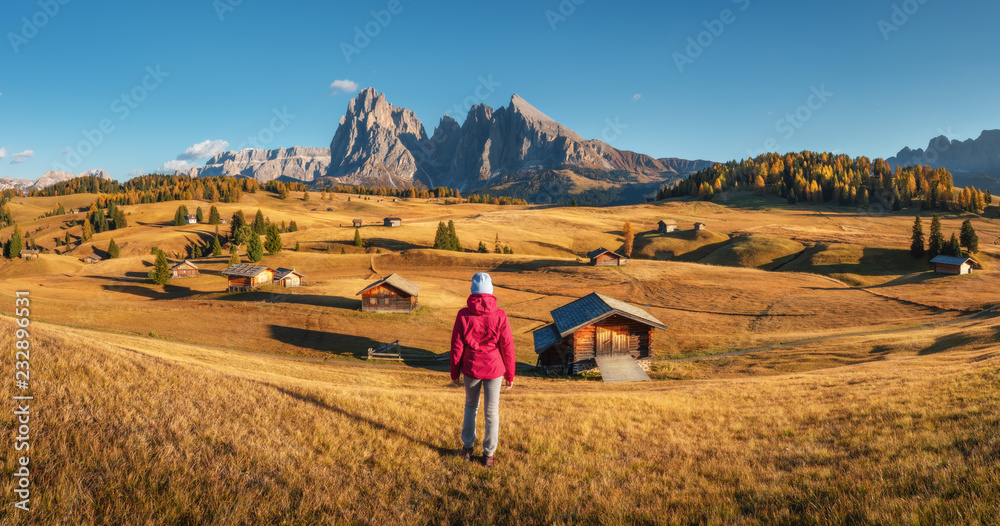 Young woman on the hill looking in meadows and mountains at sunset in autumn. Alpe di Siusi, Dolomit
