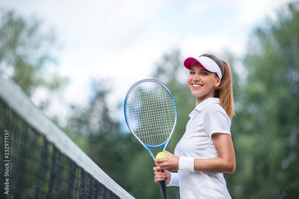 拿着网球拍微笑的年轻女孩
