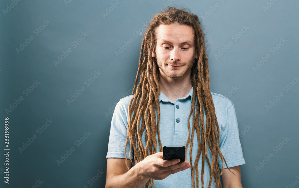 灰色背景下快乐的男人盯着手机