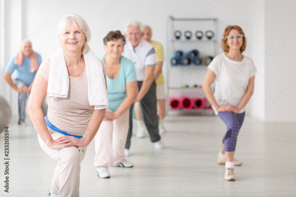 微笑的老年妇女在老年人健身课上用毛巾锻炼
