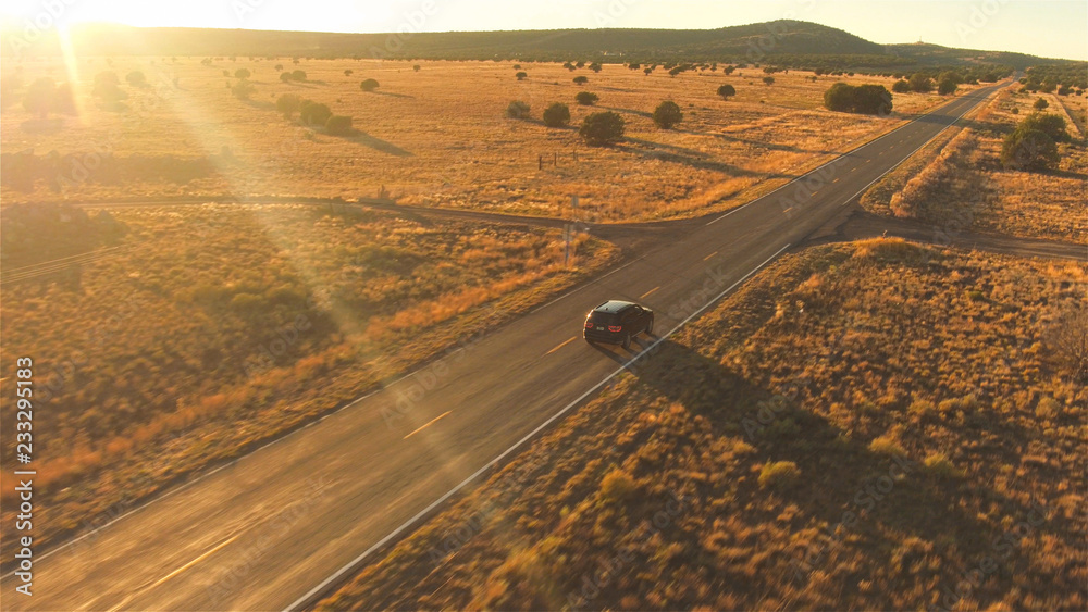 空中飞航：金色夏日日落时，黑色SUV汽车在空旷的乡村公路上行驶