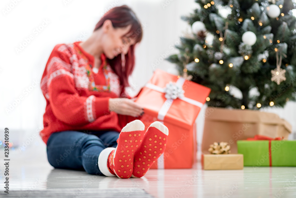 脚穿羊毛袜在圣诞树旁，女人在看礼盒