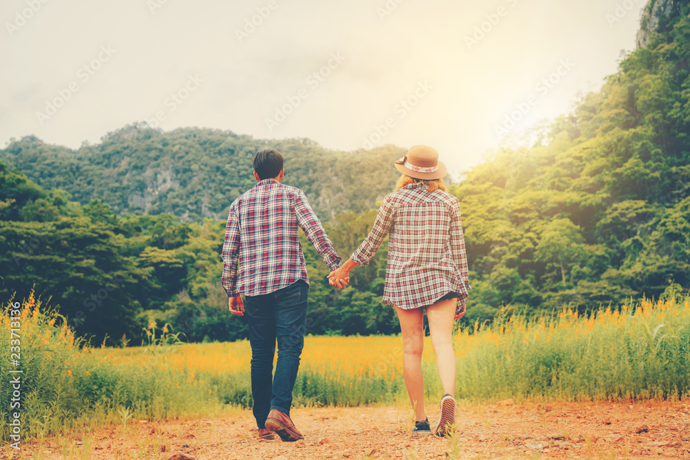 幸福的一对情侣在山上的绿草地里浪漫漫步。旅行和蜜月概念。