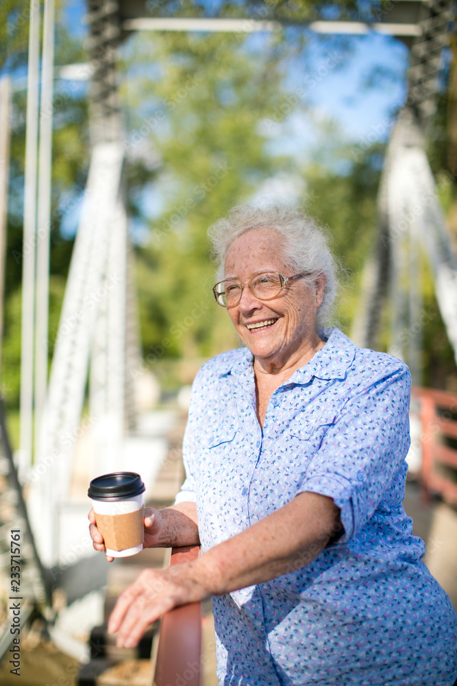 站在桥上喝咖啡的老年妇女