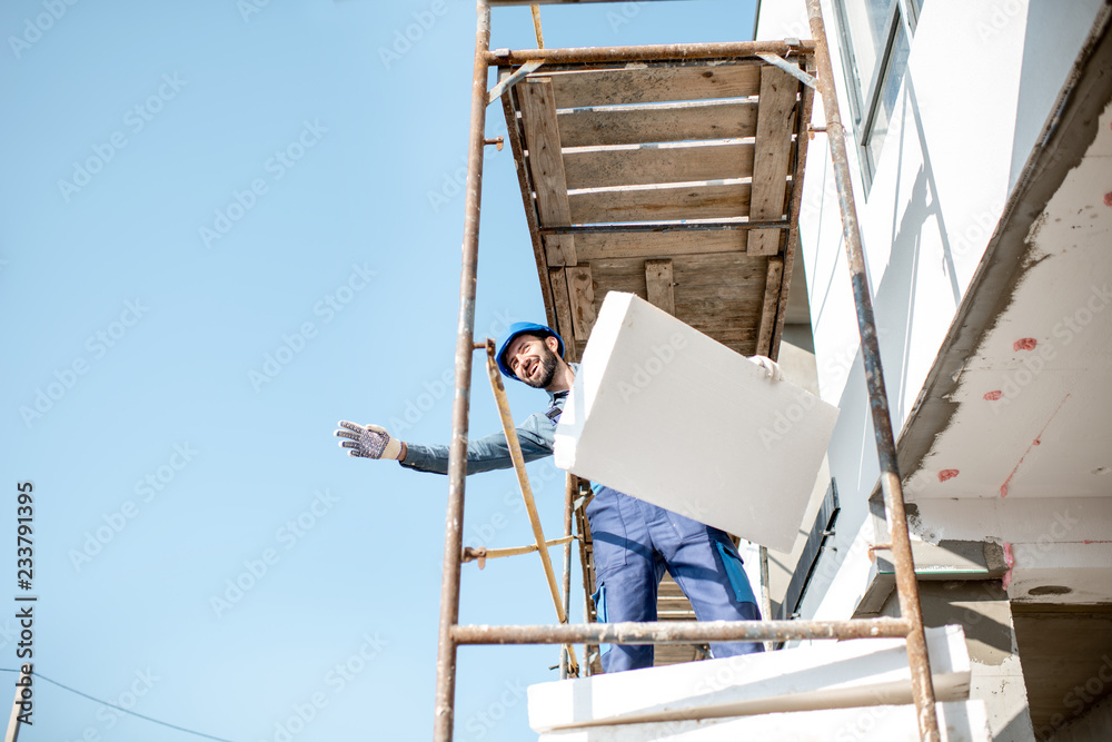 建筑工人用建筑脚手架上的泡沫板温暖建筑立面