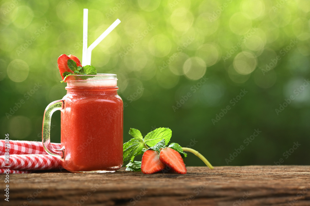 玻璃草莓奶昔，以木头和自然为背景，配切片浆果