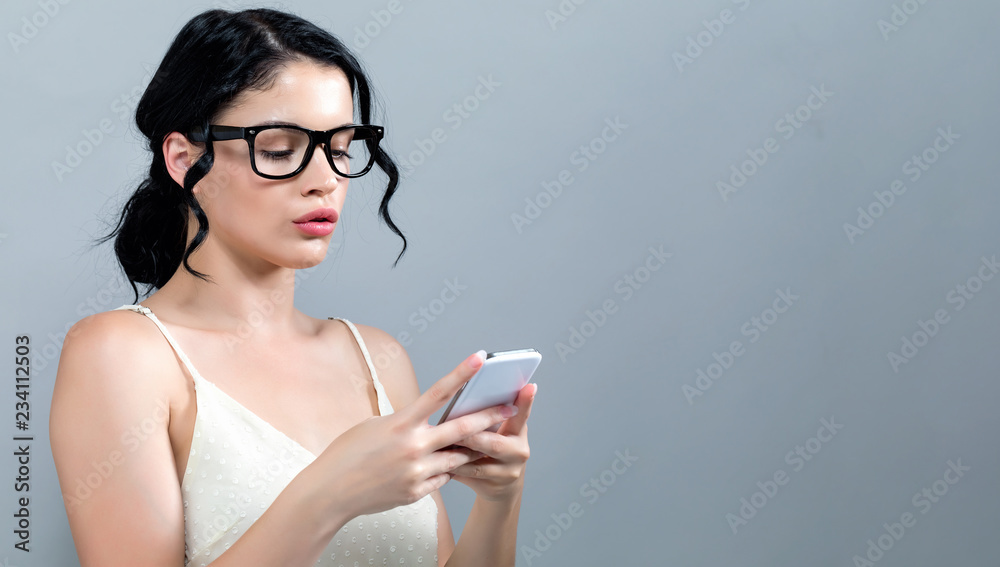 年轻女子在灰色背景下使用手机