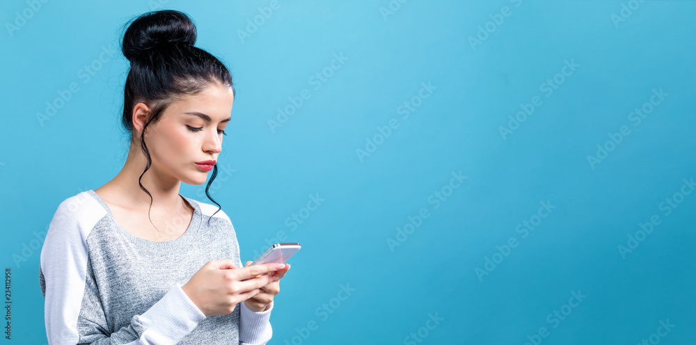 年轻女子在蓝色背景下使用手机