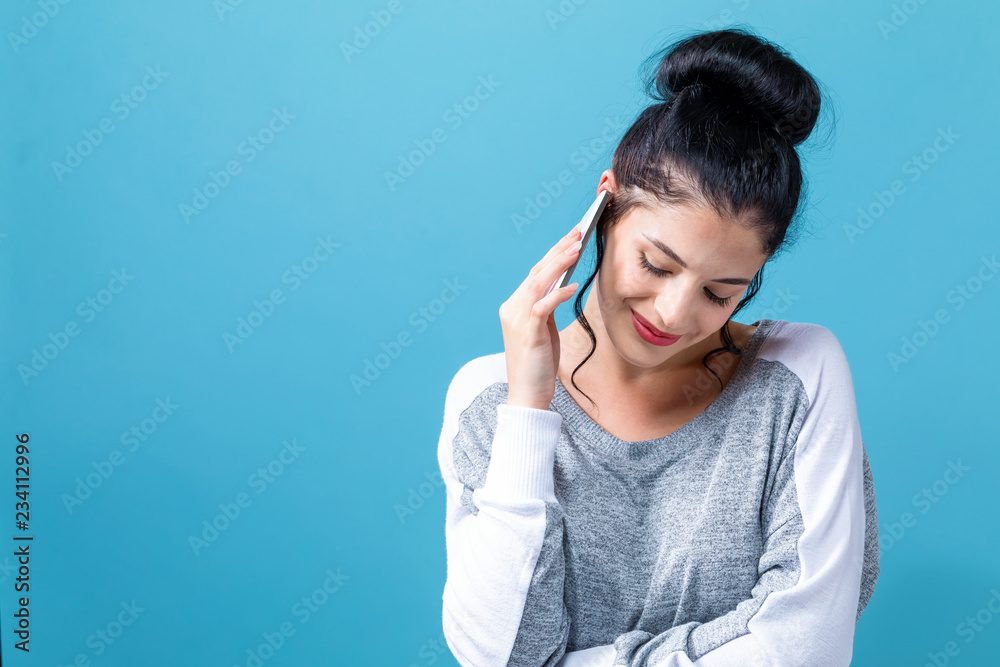 Young woman talking her the cellphone on a blue background