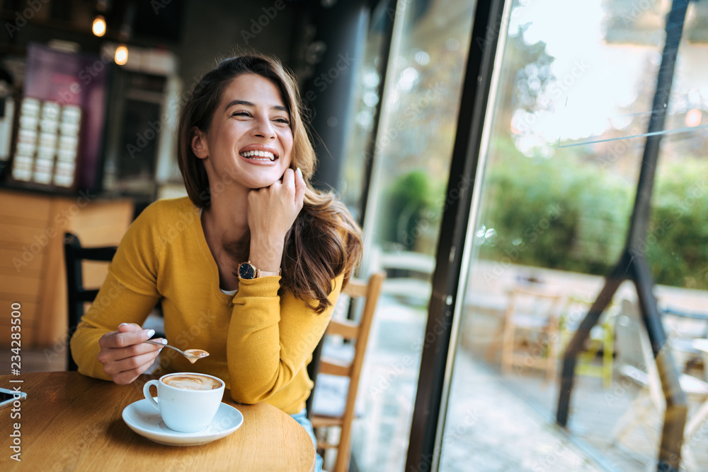 快乐的女人在咖啡馆喝咖啡。