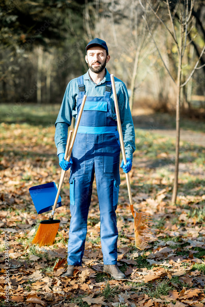 一名身穿蓝色制服、手持清扫工具的专业男性清扫员在花园里的肖像