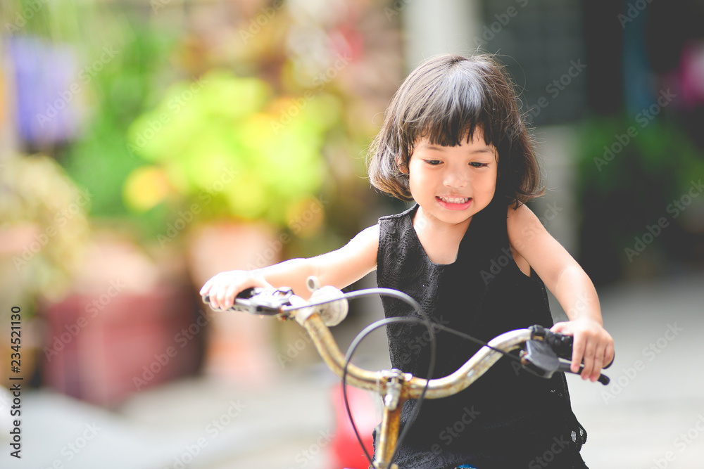 快乐的三四岁亚洲小女孩，骑自行车玩得很开心。练习，运动，孩子