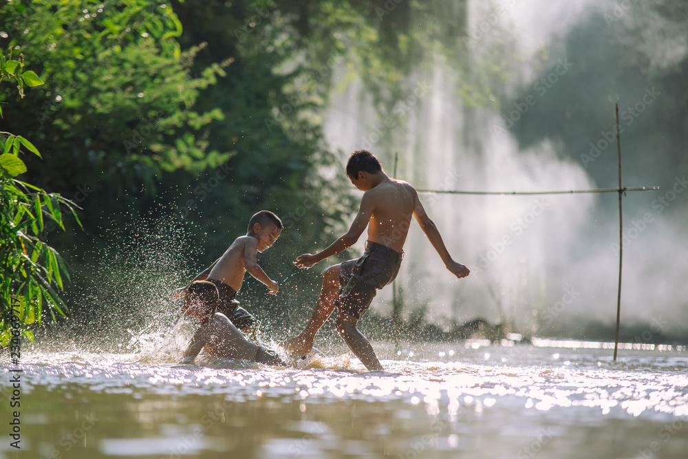 亚洲儿童在河里踢足球，体育在泰国农村和地区发挥着重要作用
